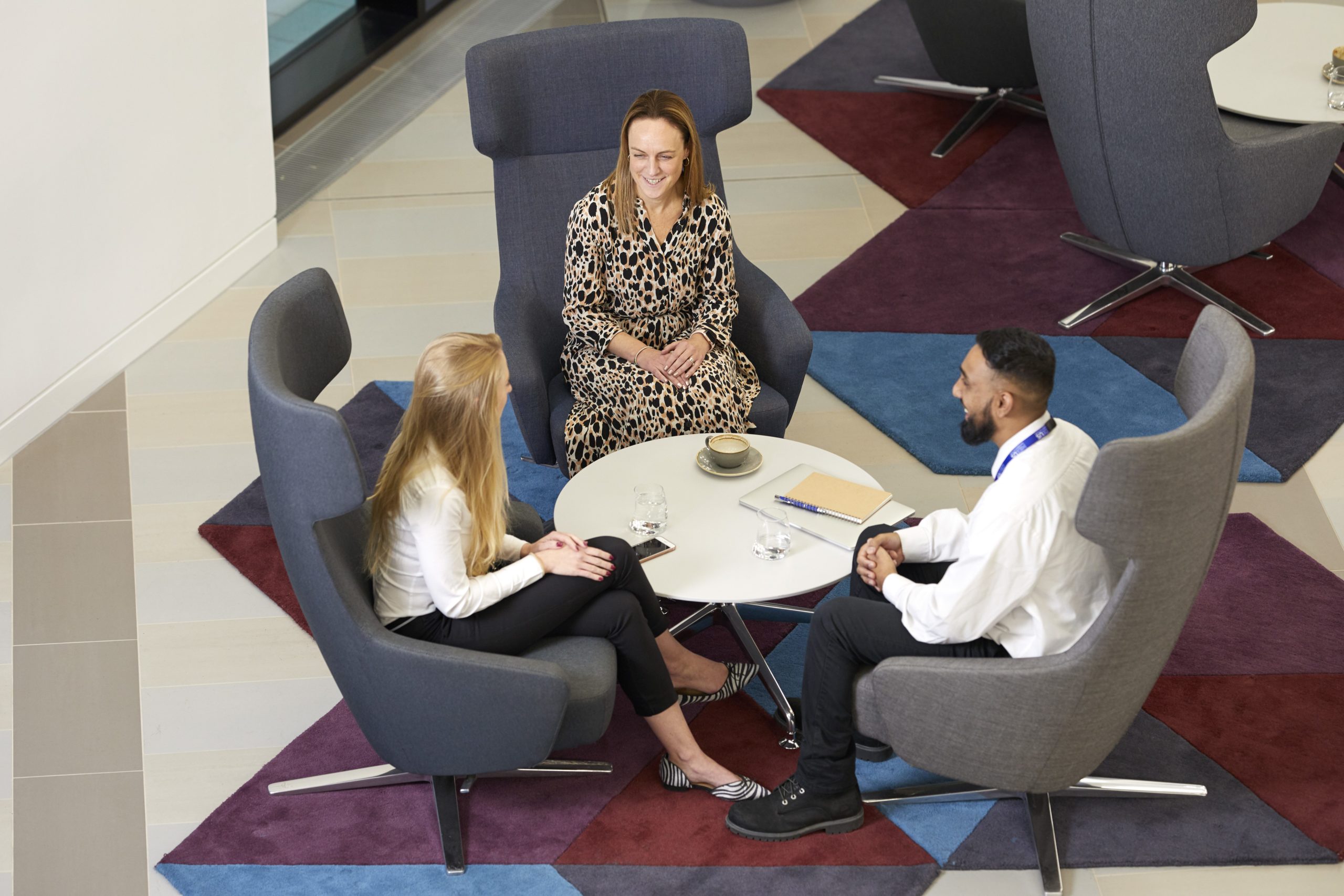 Photograph taken from above of a group sat around a small table chatting informally