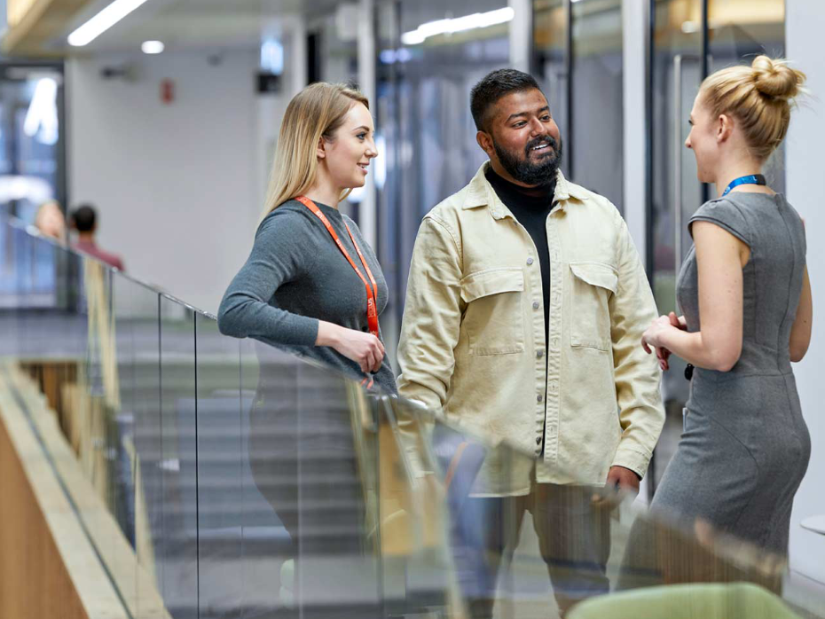 Three people stood at a banister in conversation