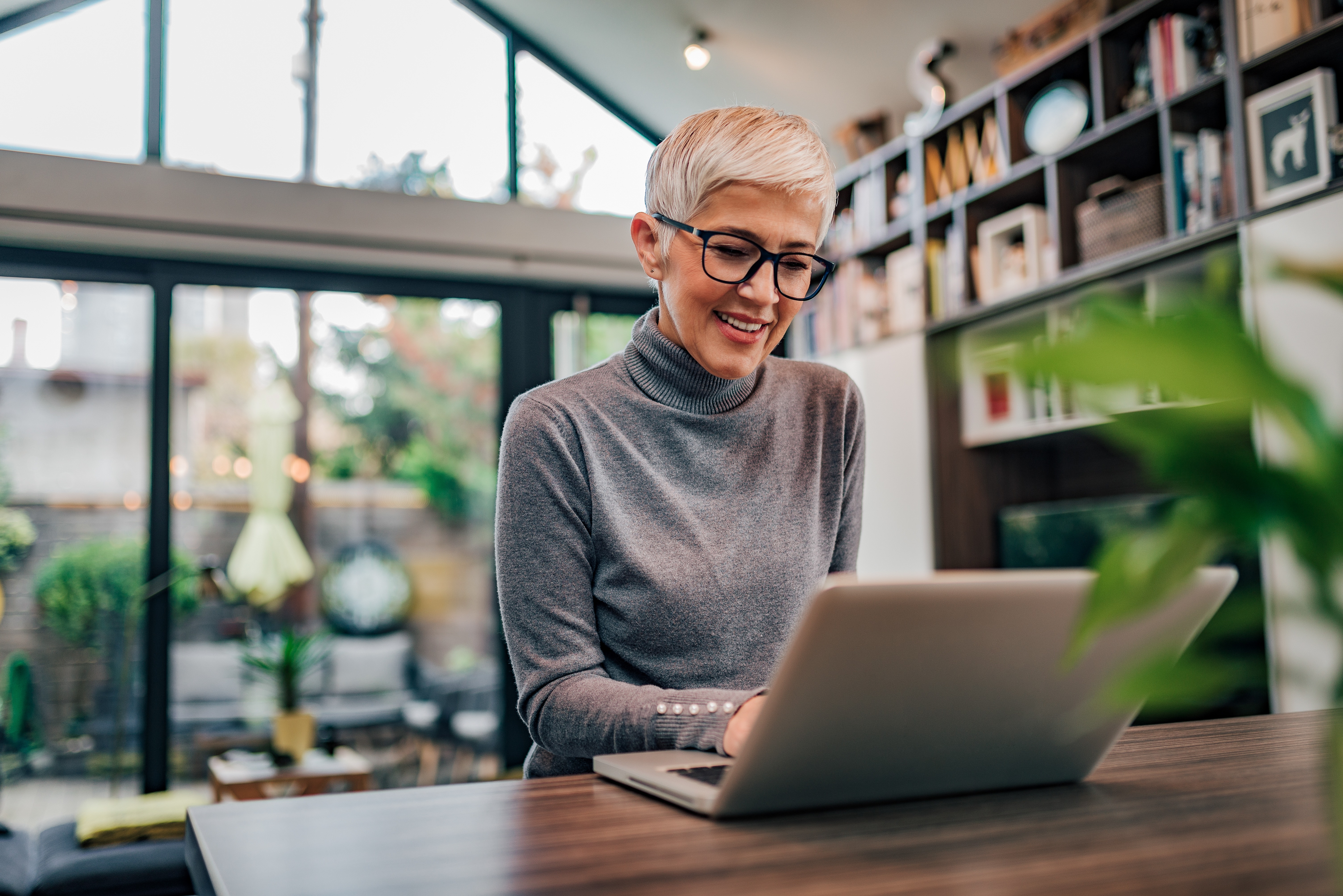 Image of female sat in home environment working at a laptop.