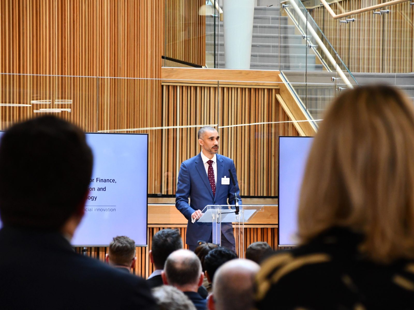 Image from the back of the audience lookin at Ezechi Britton MBE, CEO-elect of CFIT speaking at a lectern on the stage