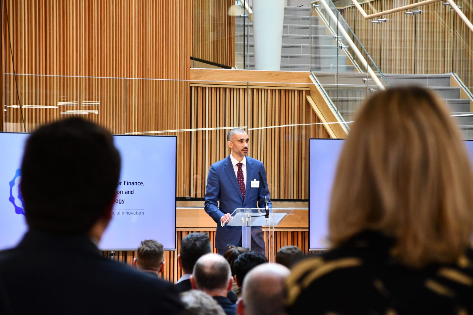 Image from the back of the audience lookin at Ezechi Britton MBE, CEO-elect of CFIT speaking at a lectern on the stage